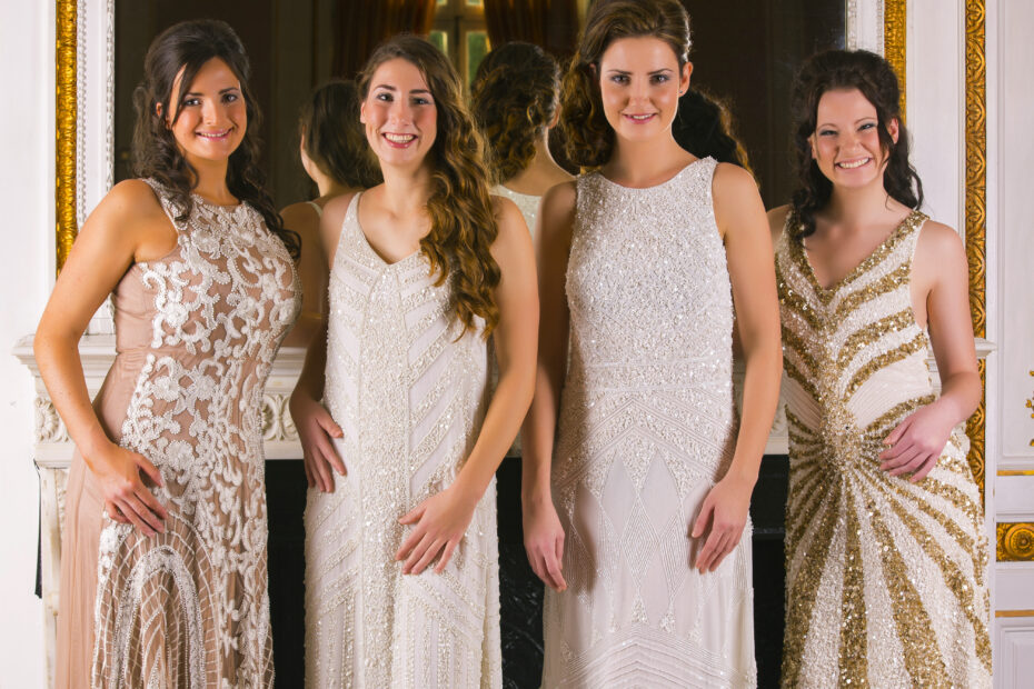 a group of young ladies in gold dresses by a fireplace
