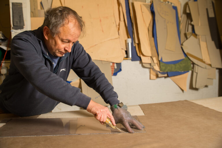 man cutting leather with a template